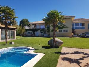 a house with a yard with a swimming pool and palm trees at Chalet San Bernardo in Toledo