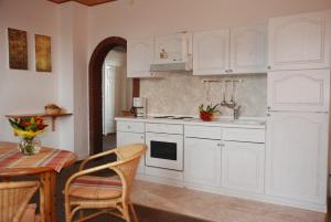 a kitchen with white cabinets and a table with chairs at Ferienhof Lange in Fehmarn