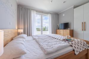 ein großes weißes Bett in einem Schlafzimmer mit Fenster in der Unterkunft Villa Sanddorn - Ferienwohnungen in Börgerende-Rethwisch
