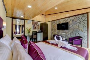 - une chambre avec un grand lit et un mur en pierre dans l'établissement Sumitel Darjeeling, à Darjeeling