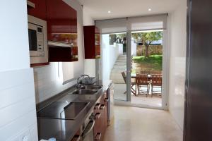 a kitchen with a sink and a door to a patio at Villa Mar in Cala en Blanes