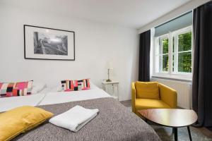 a bedroom with a bed and a chair and a window at Tia Apartments and Rooms in Zagreb