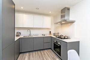 a kitchen with white cabinets and a sink and a stove at Halo House Apartments in Manchester