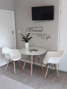 a table with two chairs and a tv on a wall at Aloe @ the Sea in Mossel Bay