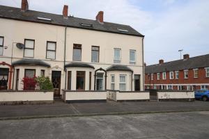 ein weißes Gebäude mit einem Parkplatz davor in der Unterkunft Shaftesbury Avenue Townhouse in Belfast