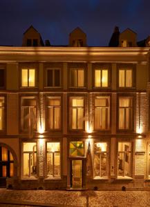 een groot gebouw met 's nachts verlichte ramen bij Hotel Les Charmes in Maastricht