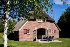 een klein bakstenen huis met een rieten dak bij Bungalowpark Hoge Hexel in Hoge-Hexel