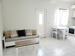 ein weißes Wohnzimmer mit einem Sofa und einem Tisch in der Unterkunft Damatria studio in Karpathos