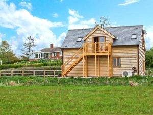 a large wooden house with a wooden deck at Rhiastyn Barn in Hyssington