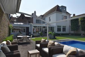 a patio with couches and a pool in front of a house at Casa Romantico in Bruges