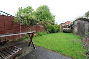 um quintal com um banco de madeira e uma cerca em Home from Home by StayStaycations em Quedgeley