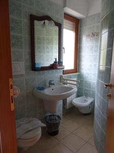 een badkamer met een wastafel, een toilet en een spiegel bij Villa Biancofiore in San Giovanni Rotondo