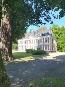 ein großes weißes Haus mit einem Baum davor in der Unterkunft Chateau Gruchet Le Valasse in Gruchet-le-Valasse