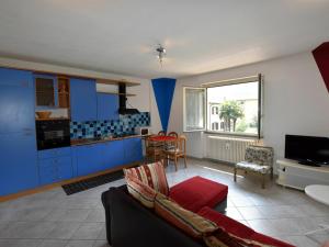 una cucina con armadi blu e un soggiorno con divano. di Belvilla by OYO Flat with terrace near the lake a Porlezza