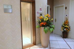 eine Vase mit Blumen im Flur mit Spiegel in der Unterkunft Hotel Busignani in Rimini