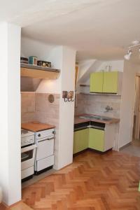 a kitchen with white and green cabinets and a wooden floor at Apartment Polane in Blejska Dobrava