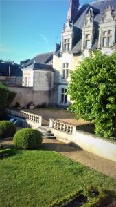 un grand bâtiment blanc avec une cour herbeuse devant dans l'établissement Gite de la petite masse, à Amboise