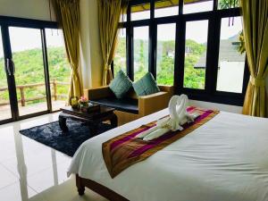 a bedroom with a large bed and a room with windows at Phangan Utopia Resort in Mae Haad