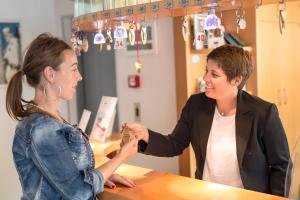 a woman is handing a woman a necklace at Hotel Maibad in Vipiteno