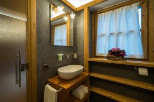 uma casa de banho com um lavatório, um espelho e uma janela em I Riviù em Branzi