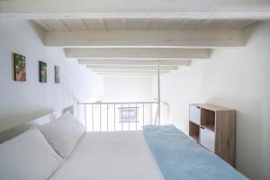Habitación blanca con cama y ventana en AlohaMundi Alameda, en Sevilla