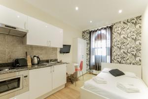 a white kitchen with a bed in a room at New Kent Apartments in London