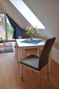 une table avec un vase avec des fleurs roses dans l'établissement Ferienhaus Müritzzauber / 1 Zimmer Dachgeschoss-Appartement, à Röbel