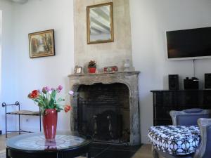 a living room with a fireplace and a vase of flowers on a table at Petite Maison Romantique Coeur Historique Plantagenet, au calme in Le Mans