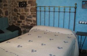 a bed in a bedroom with a blue wall at La Botería in Salas de los Infantes