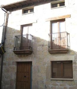 a stone building with three windows and a door at La Botería in Salas de los Infantes
