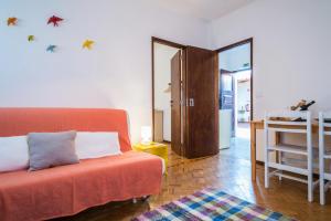 a living room with a orange couch and a kitchen at Casas do Bárrio in Alcobaça