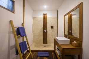een badkamer met een wastafel en een douche met een spiegel bij Orora Bungalows in Canggu