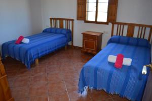 Habitación con 2 camas con colchas azules y rojas en Cas Conco, en Ciutadella