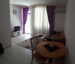 a living room with a table and chairs and a television at Aygun Apart Daire in Mahmutlar