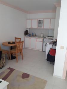 a kitchen with white cabinets and a table and chairs at Aygun Apart Daire in Mahmutlar