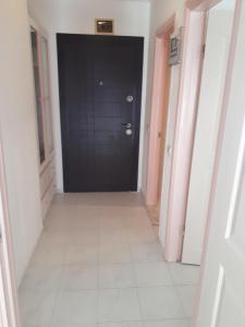 a hallway with a black door and a white tile floor at Aygun Apart Daire in Mahmutlar +4 photos