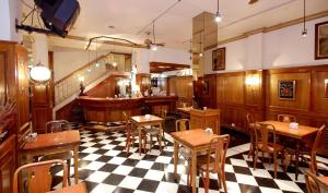 a restaurant with wooden tables and a checkered floor at Hotel Muñiz in Bahía Blanca