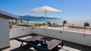 艾姆布里亞布拉瓦的住宿－Edifici Valeria，阳台配有两把椅子和一把遮阳伞,海滩