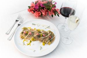 a plate of food on a table with a glass of wine at Hotel Villa Regina in Levico Terme