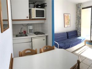 um pequeno quarto com uma mesa e uma cozinha em Residence Caraibes -Cap Coudalere, em Le Barcarès