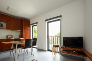 a living room with a table and a large screen television at Pedra Branca Apartments in Ericeira