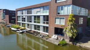 een gebouw naast een rivier met boten erin bij The Water Studio in Amsterdam