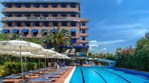 a pool with chairs and umbrellas in front of a hotel at Hotel Eur in Lido di Camaiore