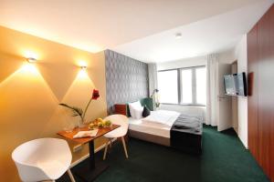 Habitación de hotel con cama, mesa y sillas en Pandion Boardinghouse en Múnich