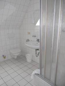 a white bathroom with a toilet and a sink at Pension Lindenhof in Kromsdorf +32 photos