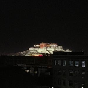a white building with lights on top of it at night at Honey Bee Hub in Lhasa