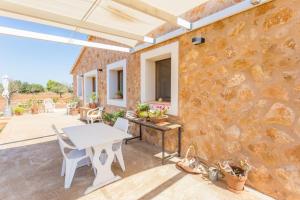 un patio con mesa, sillas y pared de piedra. en Casa Calma, en Llucmajor