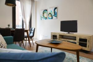 a living room with a couch and a tv and a table at APARTAMENTOS RELOJ DE BERGERÓN in Logroño