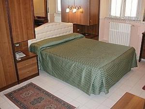 a bedroom with a bed with a green comforter at Hotel Vienna in Milan