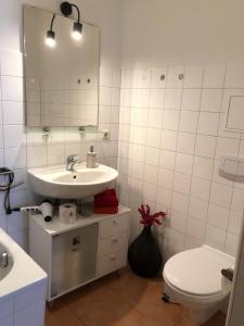 ein Badezimmer mit einem Waschbecken, einem WC und einem Spiegel in der Unterkunft Cafe 28 & Pension am Markt in Wismar